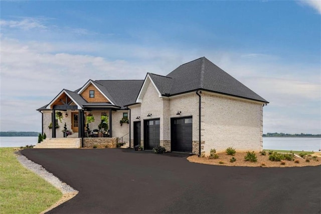 view of front of house with a garage, a porch, and a water view