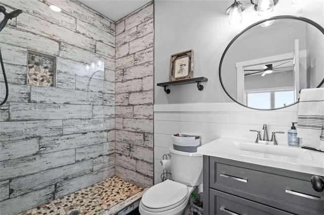 bathroom with vanity, a tile shower, ceiling fan, and toilet