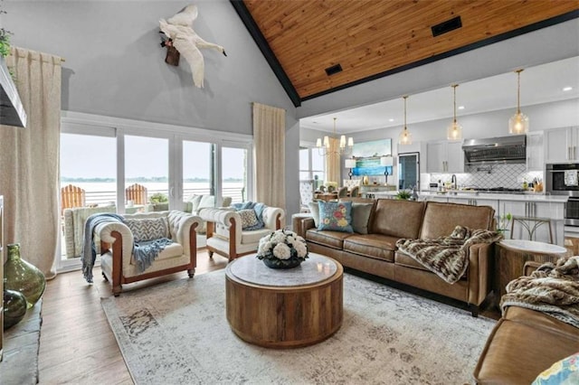 living room with high vaulted ceiling, a water view, wooden ceiling, a chandelier, and light wood-type flooring