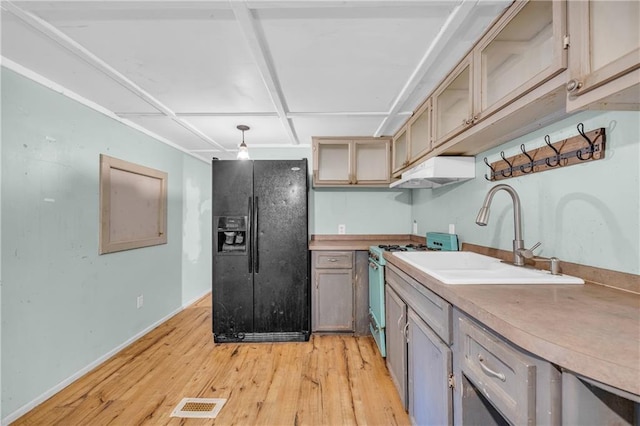 kitchen with black refrigerator with ice dispenser, gas range oven, light hardwood / wood-style flooring, and sink