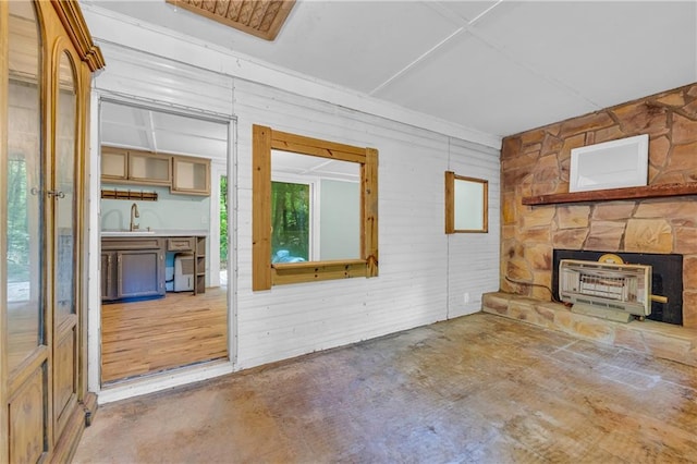 unfurnished living room featuring heating unit, a fireplace, concrete floors, and a wealth of natural light