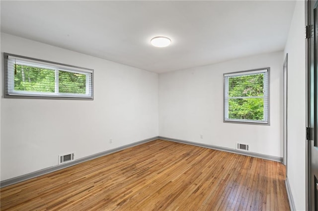 unfurnished room featuring light wood-style flooring, visible vents, and a wealth of natural light