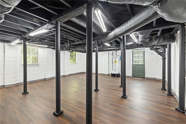 below grade area with water heater, wood finished floors, and concrete block wall