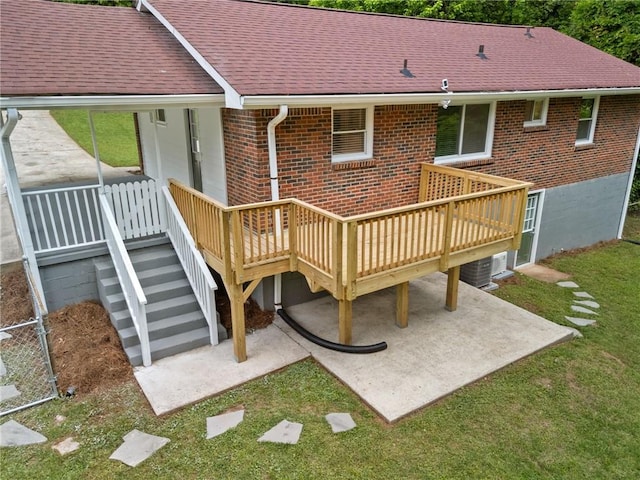 back of property featuring a deck, a patio, roof with shingles, and brick siding