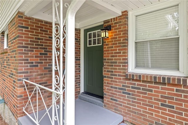 property entrance featuring a porch and brick siding
