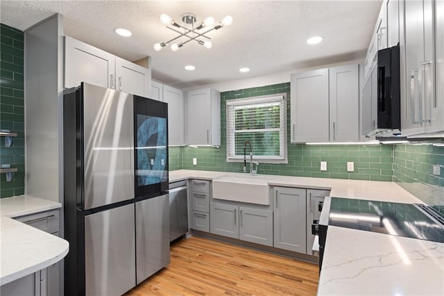 kitchen featuring light stone countertops, stainless steel appliances, backsplash, and a sink