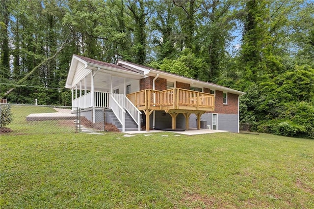 back of property with a patio, a wooden deck, a yard, brick siding, and fence