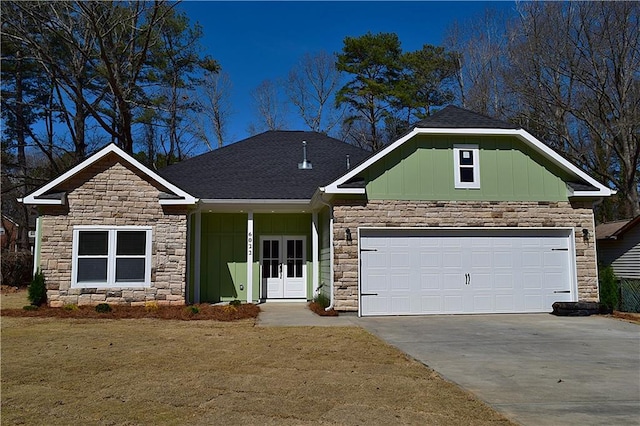 craftsman house featuring stone siding, french doors, board and batten siding, concrete driveway, and a garage