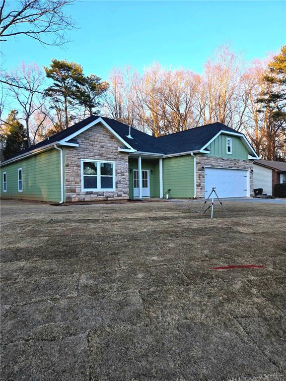 view of front of property featuring a garage, stone siding, board and batten siding, and driveway