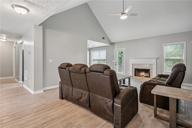 living area with light wood-style floors, high vaulted ceiling, a ceiling fan, baseboards, and a high end fireplace