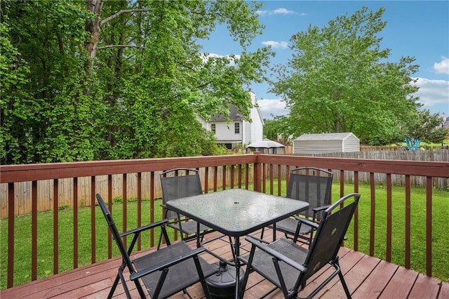 deck with outdoor dining area, a fenced backyard, and a yard