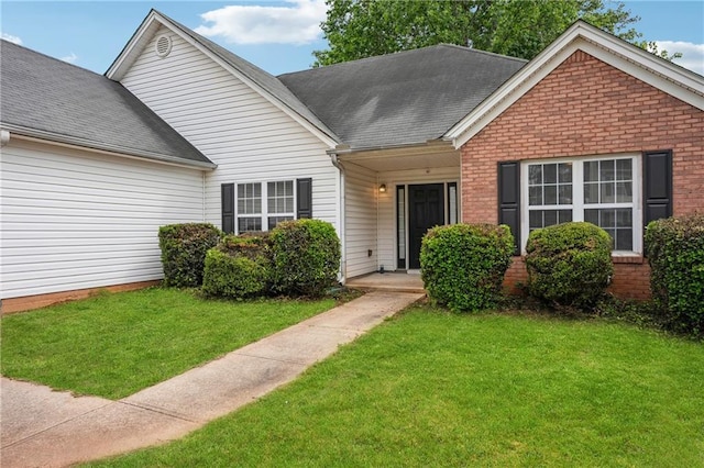single story home featuring roof with shingles, brick siding, and a front lawn