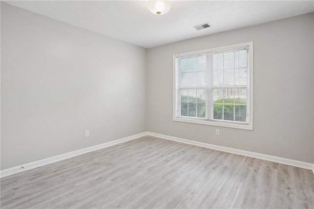 empty room featuring baseboards, visible vents, and light wood-style floors