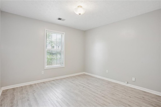 unfurnished room featuring baseboards, visible vents, a textured ceiling, and light wood-style flooring