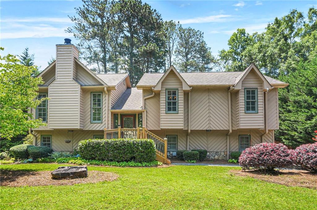 150 Victoria Sta, Woodstock, GA 30189 - view of front facade featuring a front lawn, a chimney, an outdoor fire pit, and roof with shingles