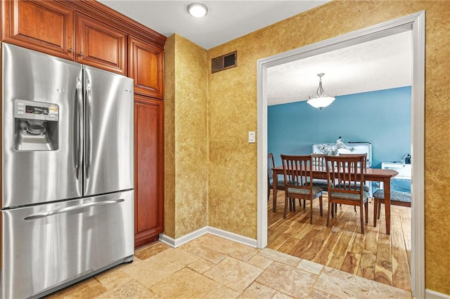 150 Victoria Sta, Woodstock, GA 30189 - kitchen featuring stainless steel refrigerator with ice dispenser, baseboards, stone tile floors, brown cabinets, and hanging light fixtures