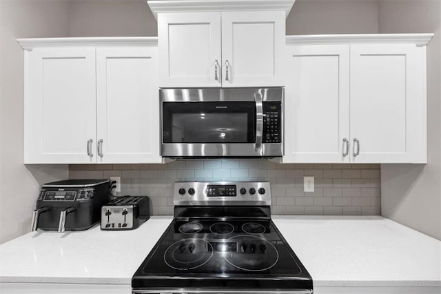 kitchen with backsplash, stainless steel appliances, and white cabinets