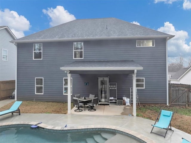 rear view of property with a fenced in pool and a patio area