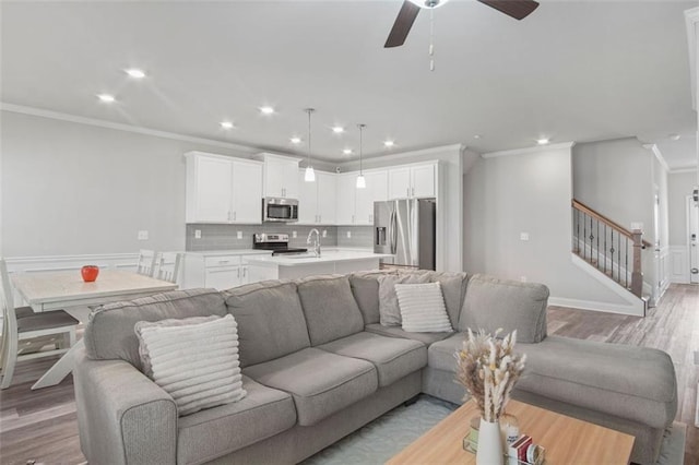 living room featuring crown molding, ceiling fan, and light wood-type flooring