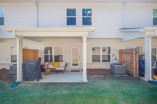 rear view of property with a lawn, central air condition unit, and a patio area