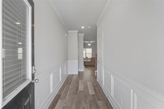 hall with ornamental molding and light hardwood / wood-style floors