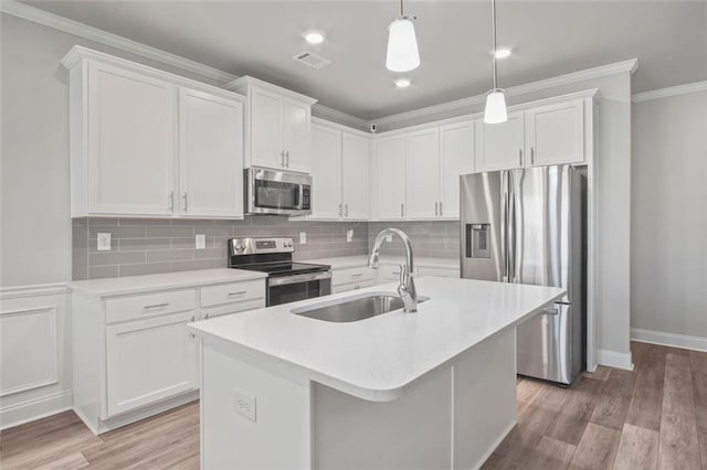 kitchen with sink, appliances with stainless steel finishes, white cabinetry, hanging light fixtures, and a center island with sink