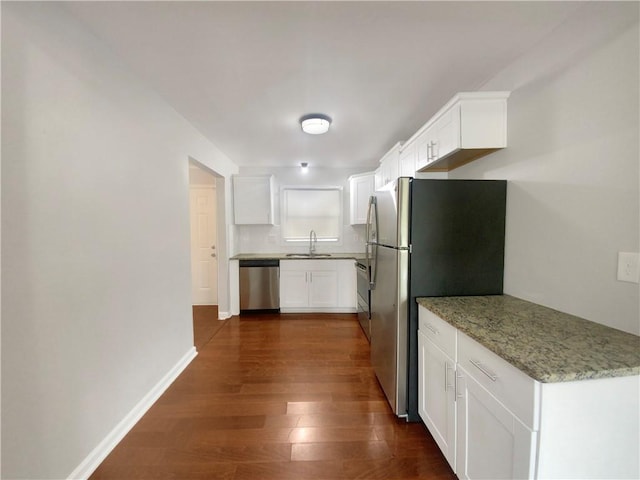 kitchen with dark wood-type flooring, light stone countertops, stainless steel appliances, white cabinets, and sink