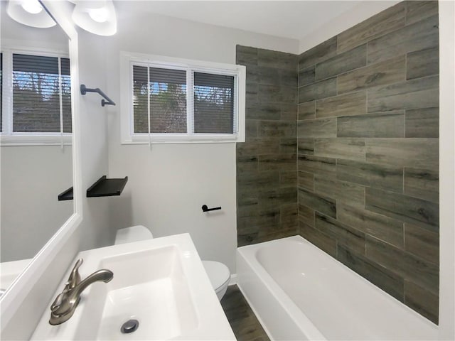 full bathroom featuring toilet, tiled shower / bath, and sink