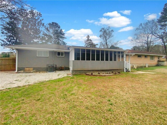 back of house featuring central AC, a sunroom, and a lawn