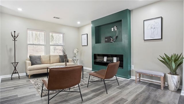 sitting room with a multi sided fireplace and wood-type flooring