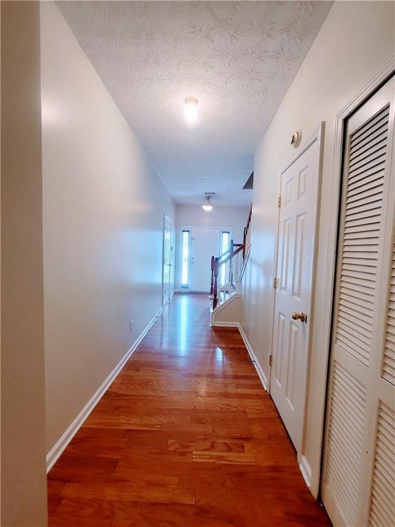 523 Lantern Wood Dr, Scottdale, GA 30079 - corridor with a textured ceiling, baseboards, and wood finished floors