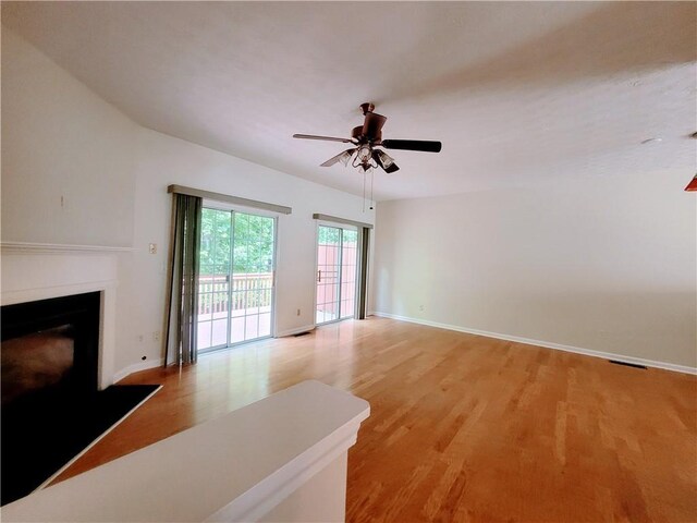 523 Lantern Wood Dr, Scottdale, GA 30079 - unfurnished living room with baseboards, a fireplace, a ceiling fan, and light wood-type flooring