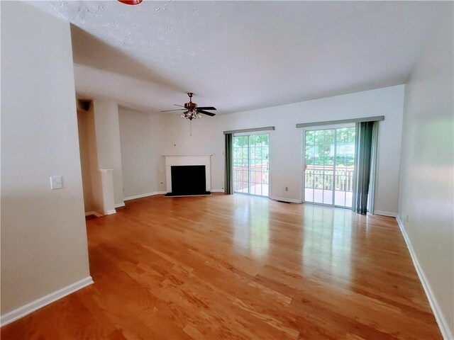 523 Lantern Wood Dr, Scottdale, GA 30079 - unfurnished living room featuring baseboards, a fireplace, a ceiling fan, and light wood-style flooring