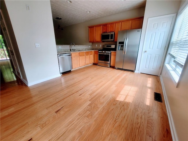 523 Lantern Wood Dr, Scottdale, GA 30079 - kitchen featuring light stone countertops, baseboards, a sink, light wood finished floors, and stainless steel appliances
