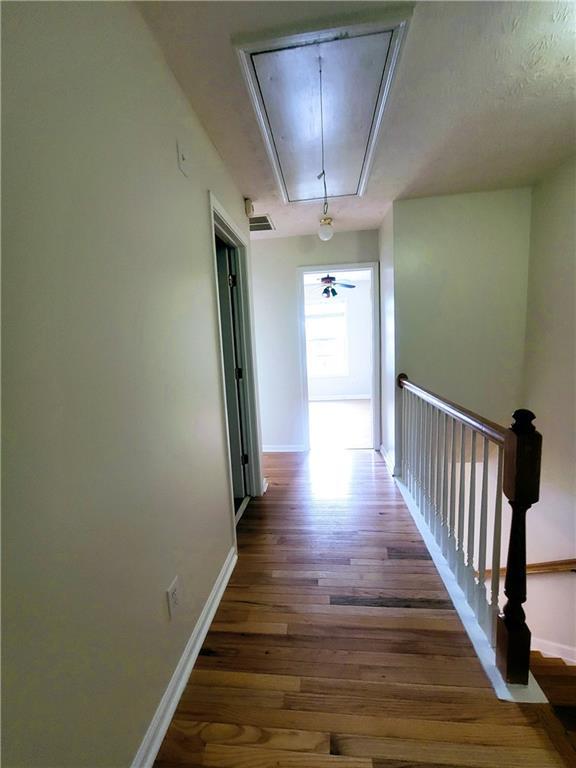 523 Lantern Wood Dr, Scottdale, GA 30079 - corridor featuring attic access, baseboards, an upstairs landing, wood finished floors, and visible vents