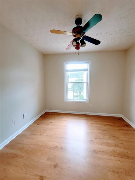 523 Lantern Wood Dr, Scottdale, GA 30079 - empty room featuring baseboards, a ceiling fan, light wood-style flooring, and a textured ceiling