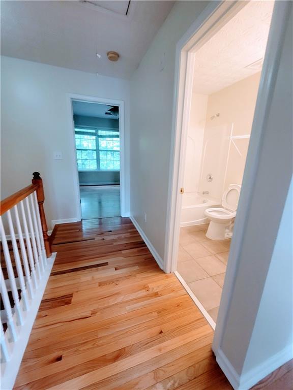 523 Lantern Wood Dr, Scottdale, GA 30079 - corridor featuring baseboards, light wood-style flooring, and an upstairs landing
