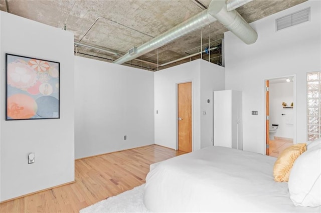 3235 Roswell Rd NE Unit 702, Atlanta, GA 30305 - bedroom featuring wood finished floors, a high ceiling, and ensuite bath