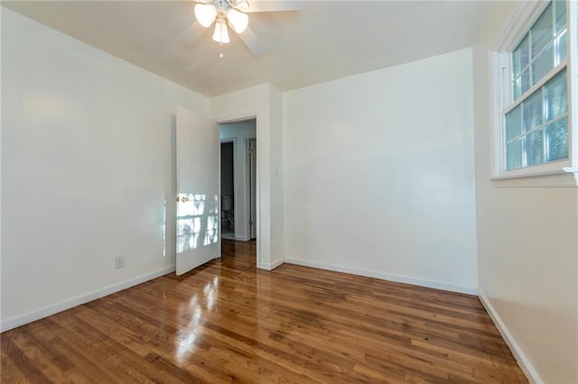 empty room with a ceiling fan, baseboards, and wood finished floors