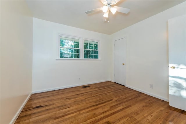 unfurnished room featuring a ceiling fan, wood finished floors, visible vents, and baseboards