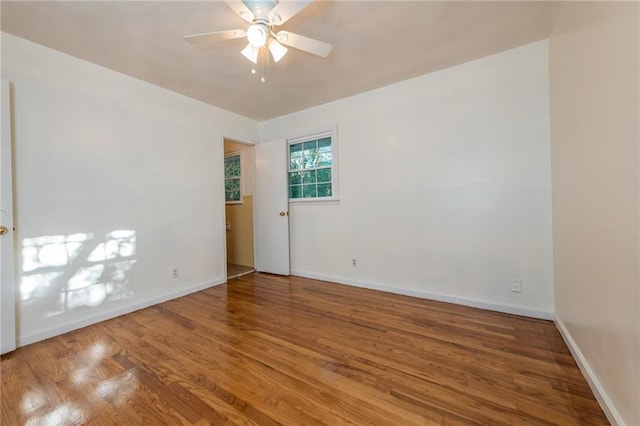 unfurnished room featuring ceiling fan, wood finished floors, and baseboards