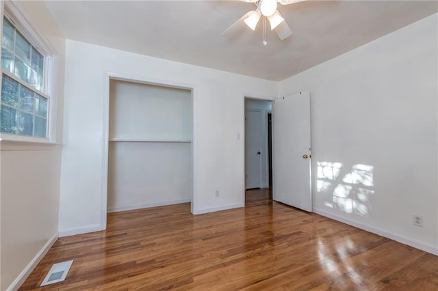 unfurnished bedroom featuring baseboards, a closet, visible vents, and wood finished floors