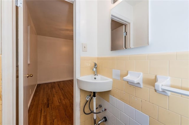 bathroom featuring wainscoting, a sink, tile walls, and wood finished floors