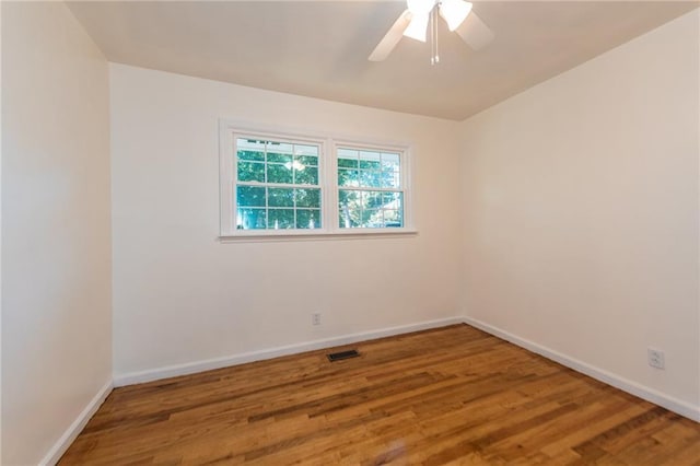 empty room featuring visible vents, ceiling fan, baseboards, and wood finished floors