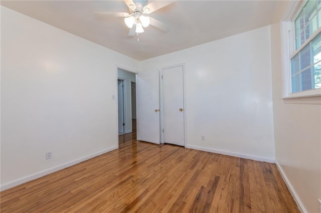 empty room featuring ceiling fan, baseboards, and wood finished floors