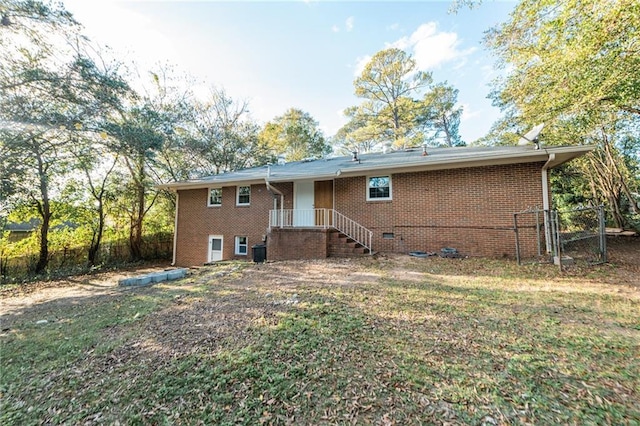 back of house with brick siding, crawl space, and fence