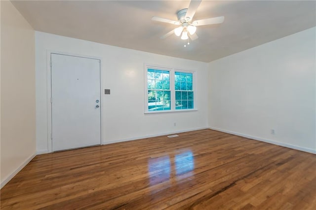 spare room with wood finished floors, a ceiling fan, and baseboards