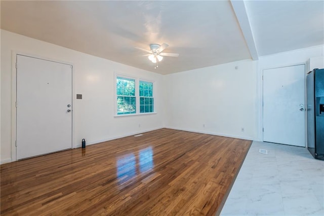 unfurnished living room with a ceiling fan, baseboards, and wood finished floors