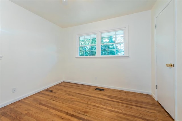 unfurnished room featuring visible vents, light wood-style flooring, and baseboards