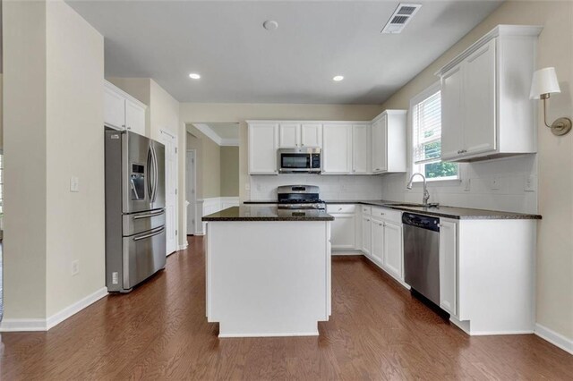 213 Roseman Way, Woodstock, GA 30188 - kitchen featuring appliances with stainless steel finishes, dark stone countertops, dark wood finished floors, white cabinets, and a center island